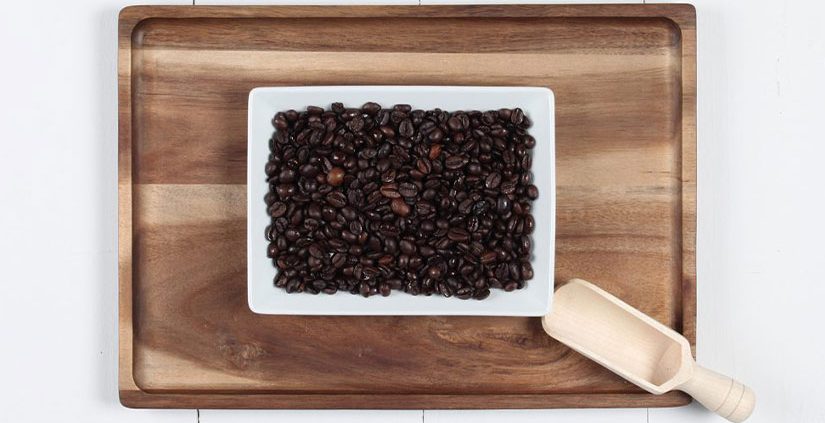 bohnenbild-passalacqua-cremador Kaffeebohnen auf weißem Teller, darunter ein Holztablett