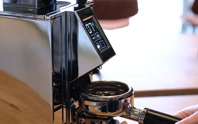 Elektrische Kaffeemühle wird mit Siebträger bedient