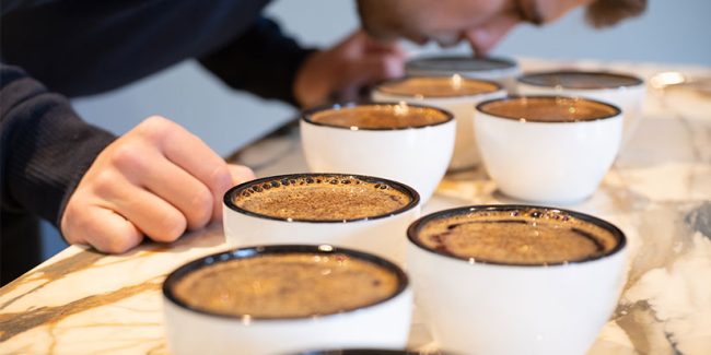 Person riecht an Kaffeebecher
