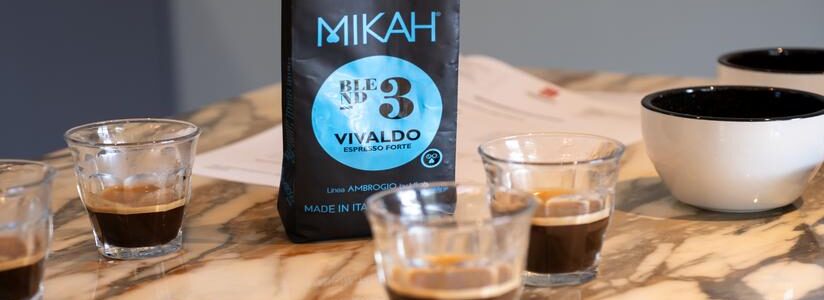 Gläser mit Espresso auf Marmorplatte, dahinter Kaffeeverpackung