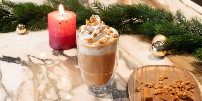 Kaffee-Latte im Glas mit Sahne und Karamellstückchen