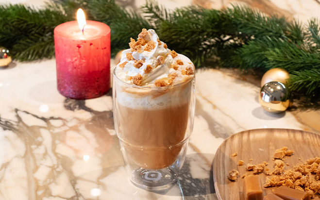 Kaffee-Latte im Glas mit Sahne und Karamellstückchen