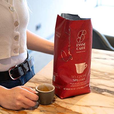 Rote Verpackung des Essse Selezione Speciale. Frau hält Espressotasse daneben.